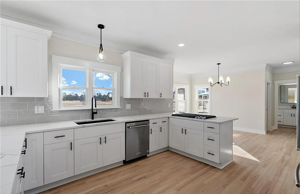 Renovated kitchen with white shaker cabinetry, subway-tile backsplash, quartz counters and a peninsula cooktop