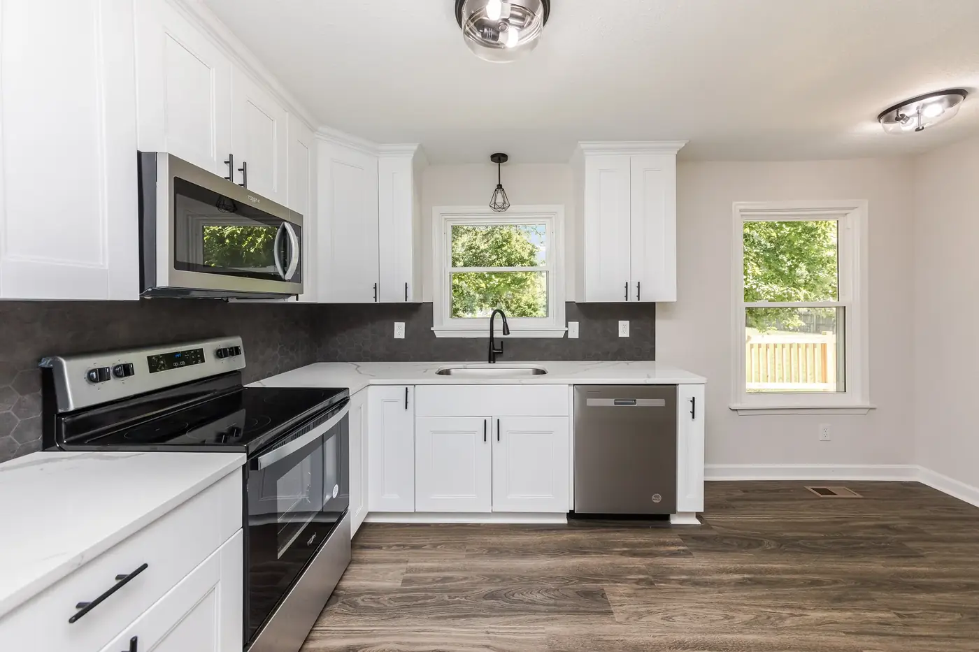 Kitchen with white cabinetry, dark counters and stainless appliances